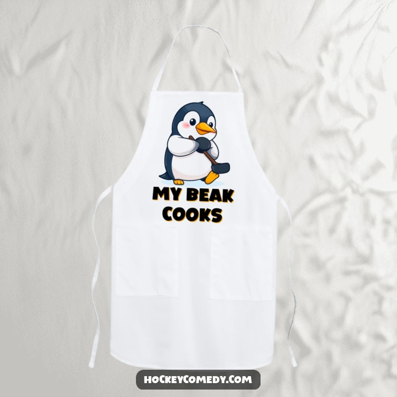 Funny penguin hockey apron, depicting a determined penguin batting a puck with its beak during kitchen tasks.