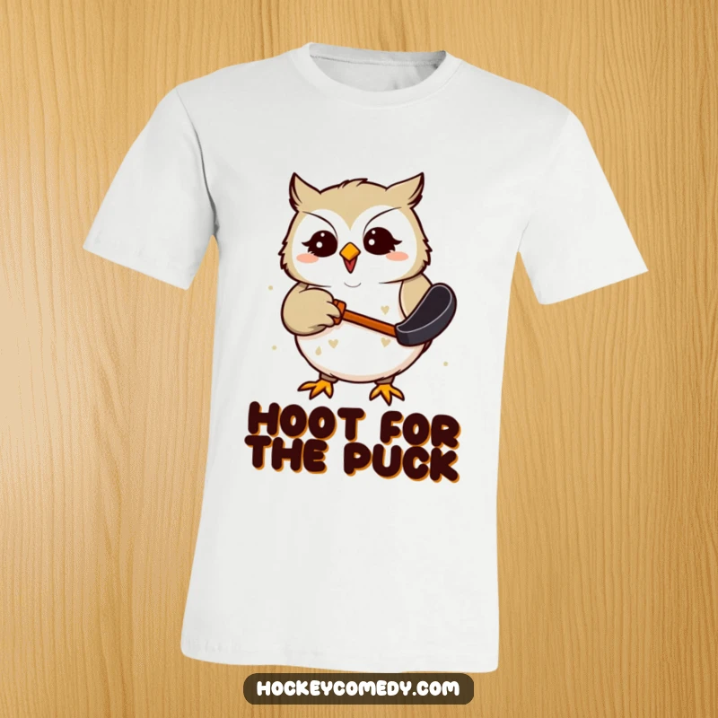 Funny T-Shirt depicting a giggling owl focused on catching a hockey puck with its beak, radiating amusement and playful energy.